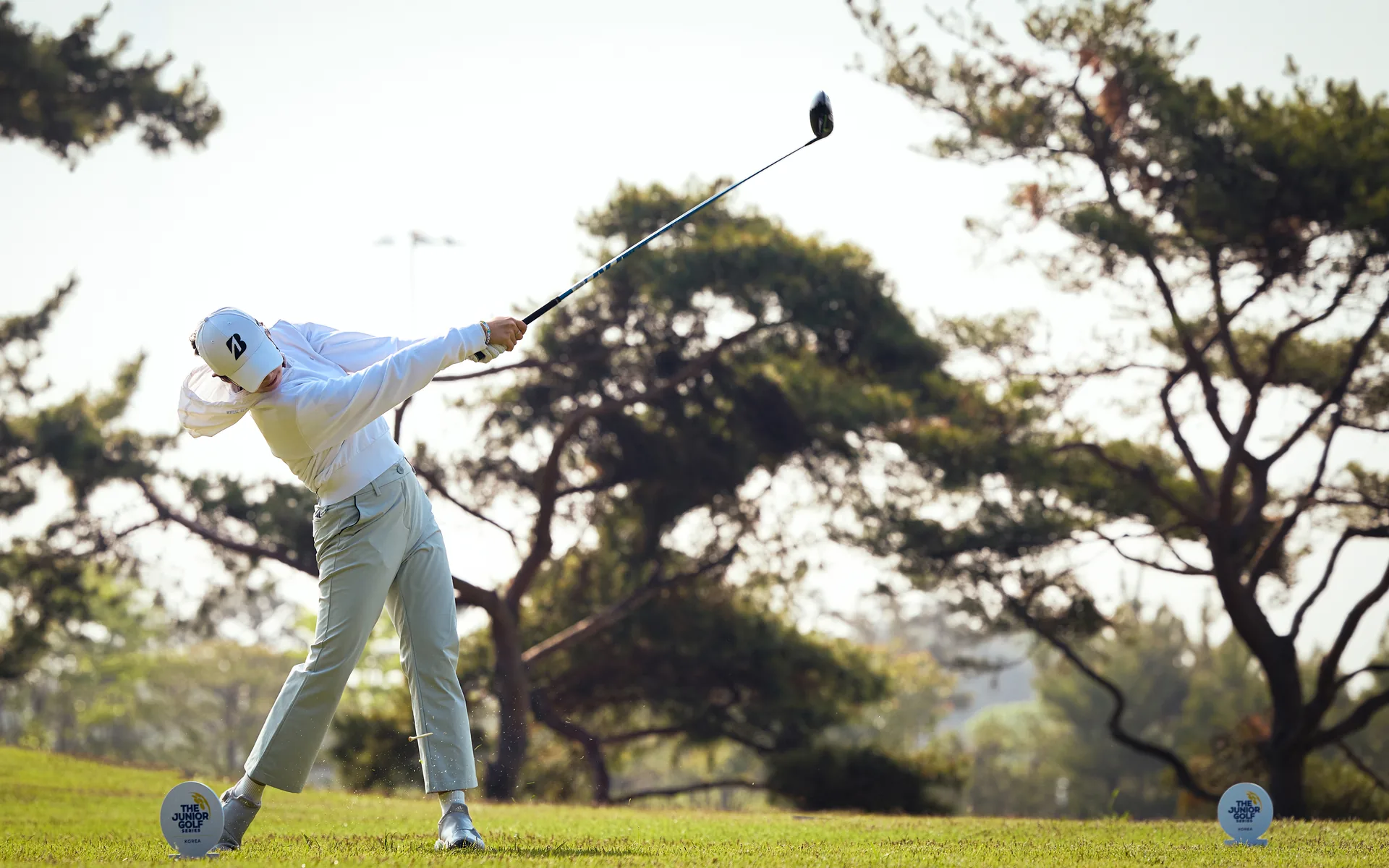 Junior golfer mid-swing against the sunrise