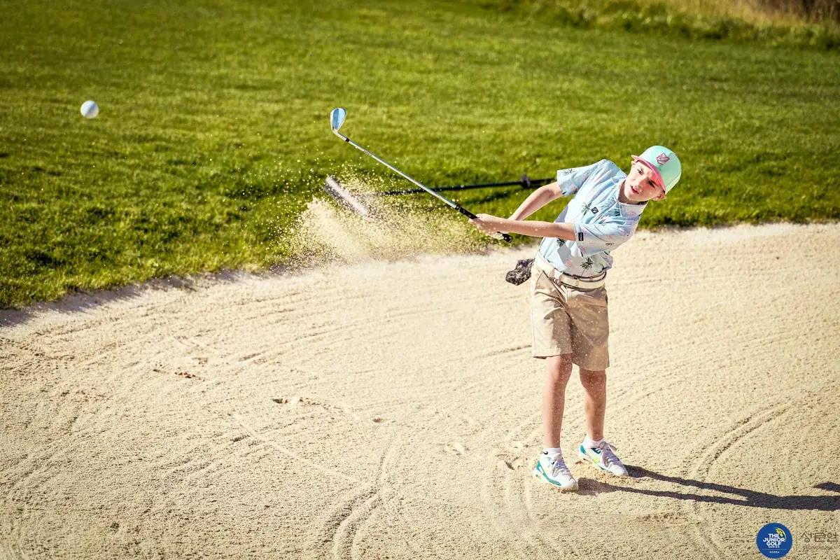 Junior golfer playing out of a greenside bunker