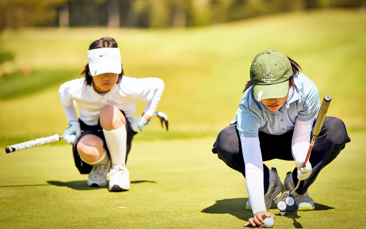 Young golfers reading the green together