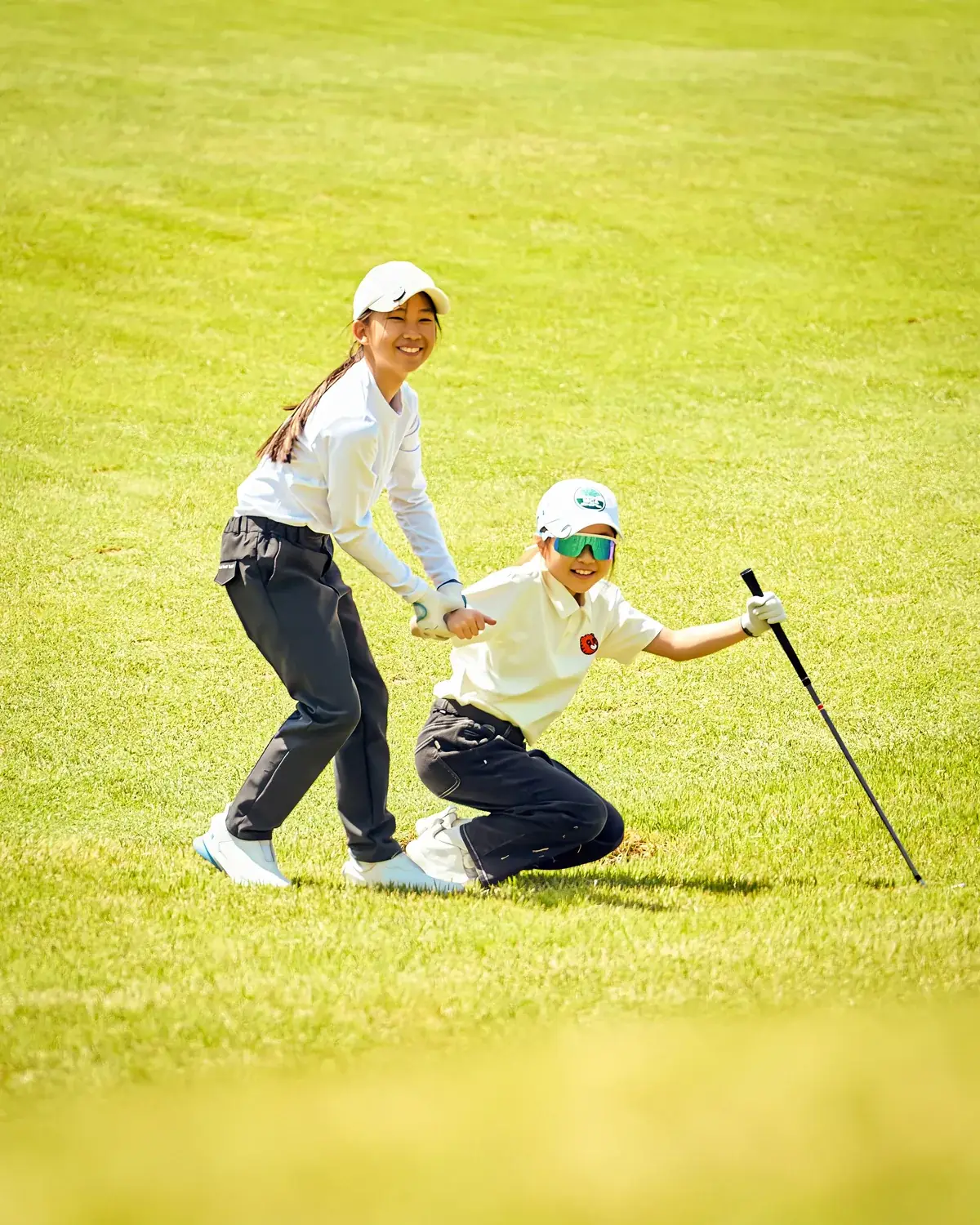 Parent coaching a junior golfer on the green