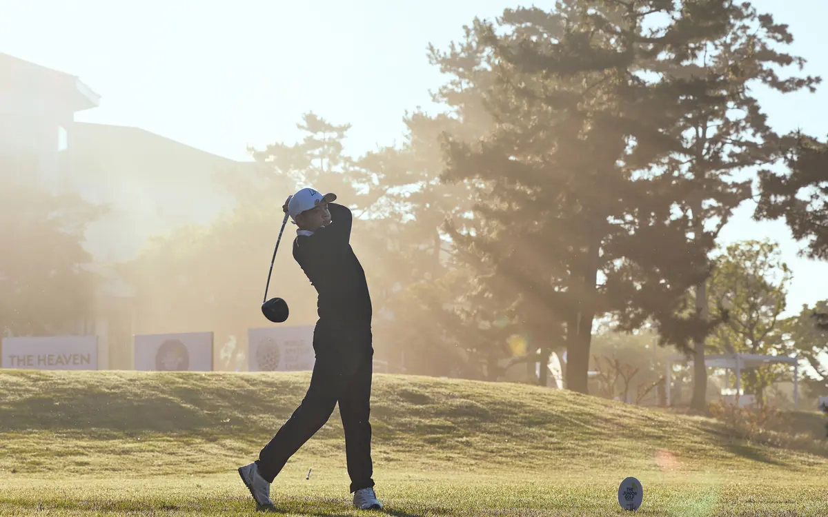 Junior golfer mid-swing at sunrise